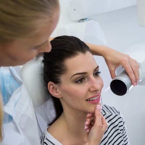 Dentist taking a female patients tooth x-ray in clinic